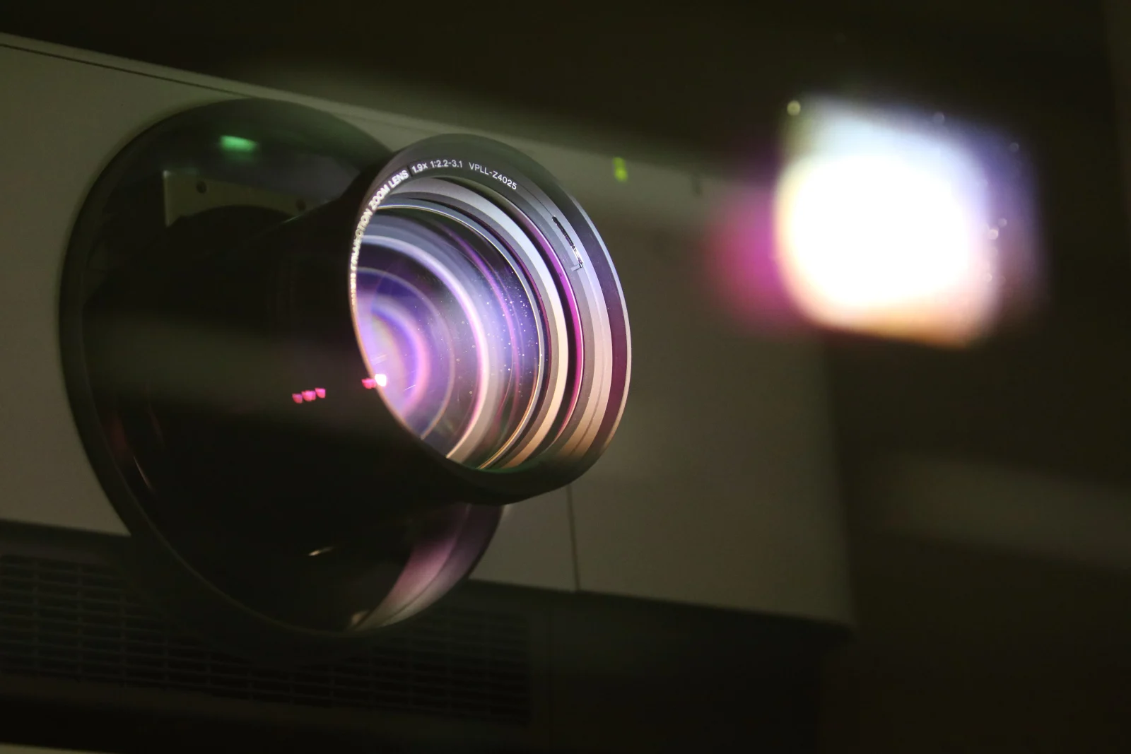 Detailed view of a projector lens emitting light, showcasing optical technology.