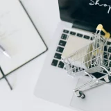 Creative depiction of online shopping with a miniature cart on a laptop keyboard.