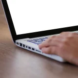 Close-up of a hand using a laptop with a blank screen, ideal for adding custom content.