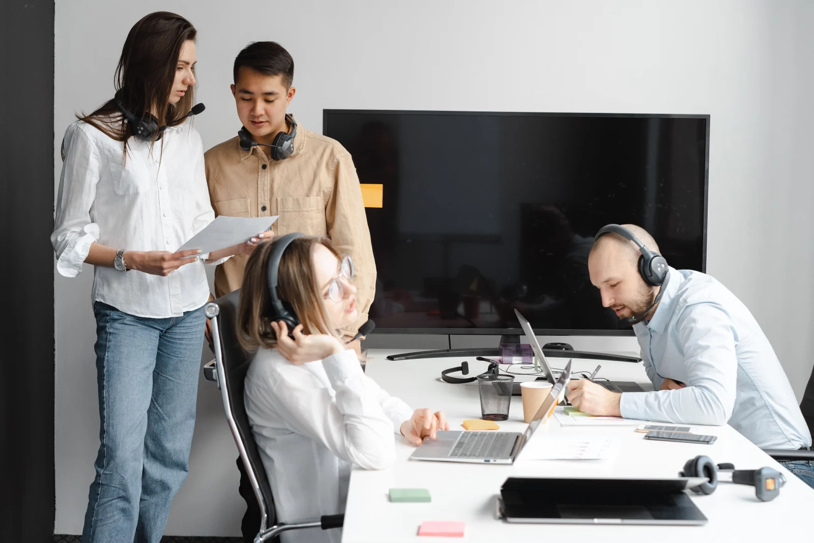 Diverse team of professionals collaborating in a modern office with tech gadgets and headsets.
